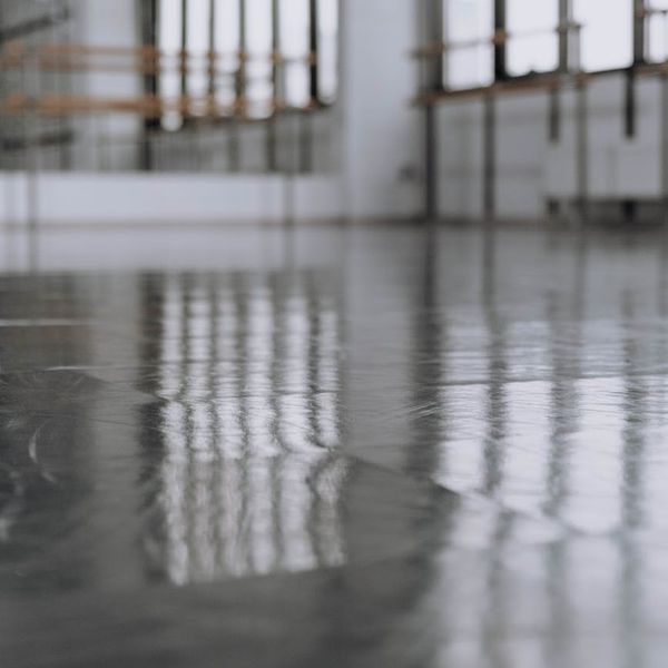 Bright and clean studio interior with large windows and exercise mats.